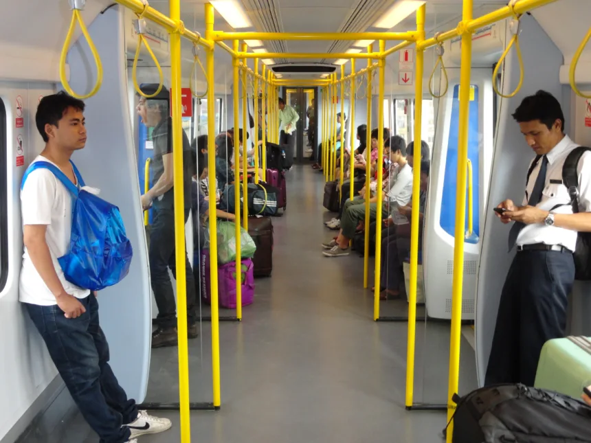 Une rame de l'Airport Rail Link à quai dans une gare de Bangkok, avec des passagers sur le quai.