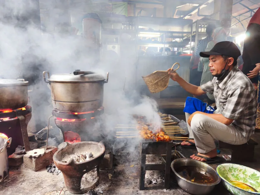 Un vendeur de rue grillant des brochettes de satay sur un marché traditionnel de Yogyakarta