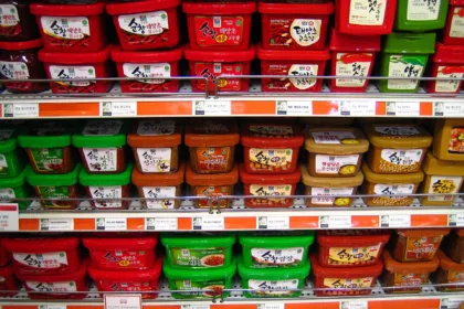 Des rayons de supermarché coréen remplis de pots rouges de gochujang et de pots de pâte de soja
