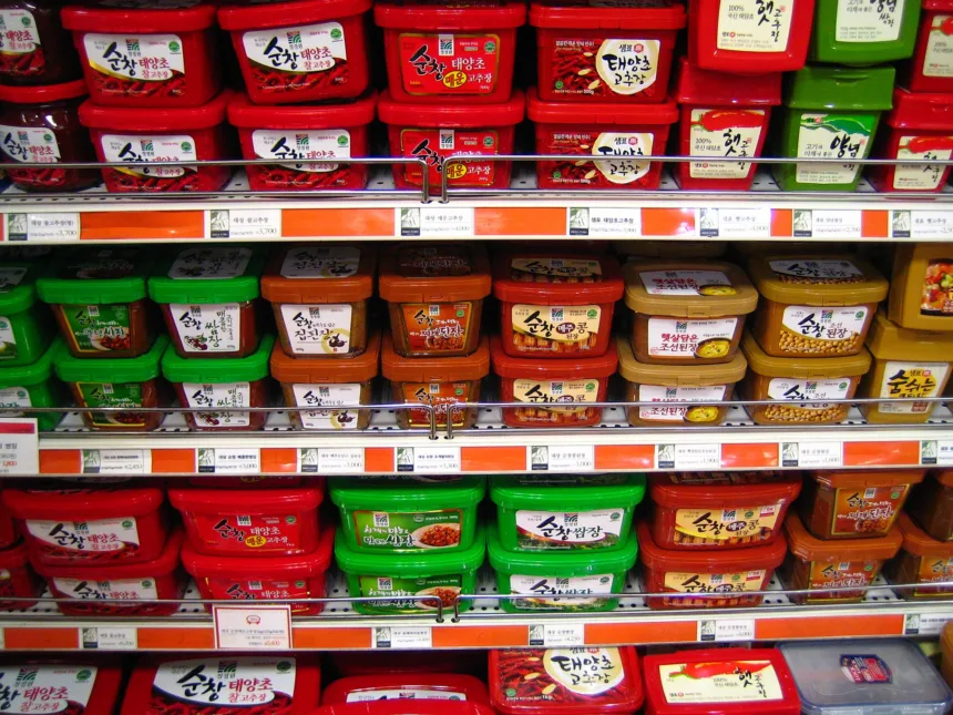 Des rayons de supermarché coréen remplis de pots rouges de gochujang et de pots de pâte de soja