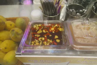 Un bol de nam pla prik, piments rouges et verts émincés dans la sauce de poisson, posé sur une table thaïlandaise
