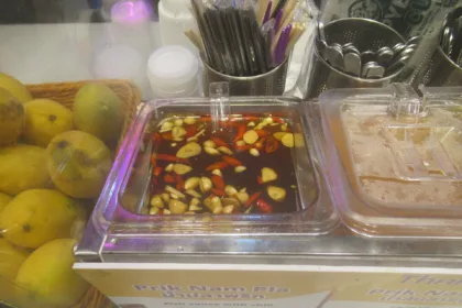 Un bol de nam pla prik, piments rouges et verts émincés dans la sauce de poisson, posé sur une table thaïlandaise