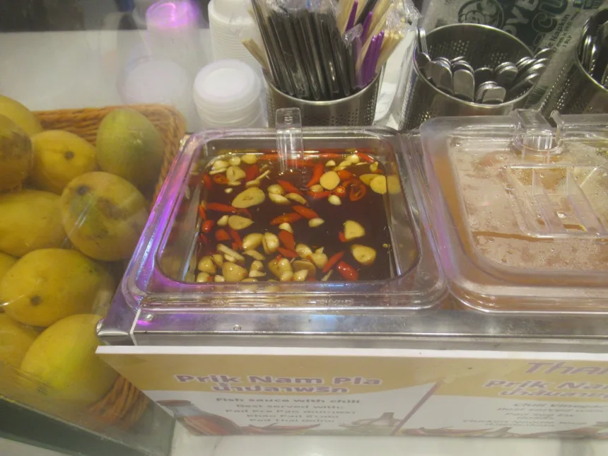 Un bol de nam pla prik, piments rouges et verts émincés dans la sauce de poisson, posé sur une table thaïlandaise
