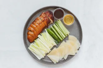 Des crêpes de canard laqué avec sauce hoisin, oignons et concombre, prêtes à être roulées