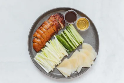 Des crêpes de canard laqué avec sauce hoisin, oignons et concombre, prêtes à être roulées