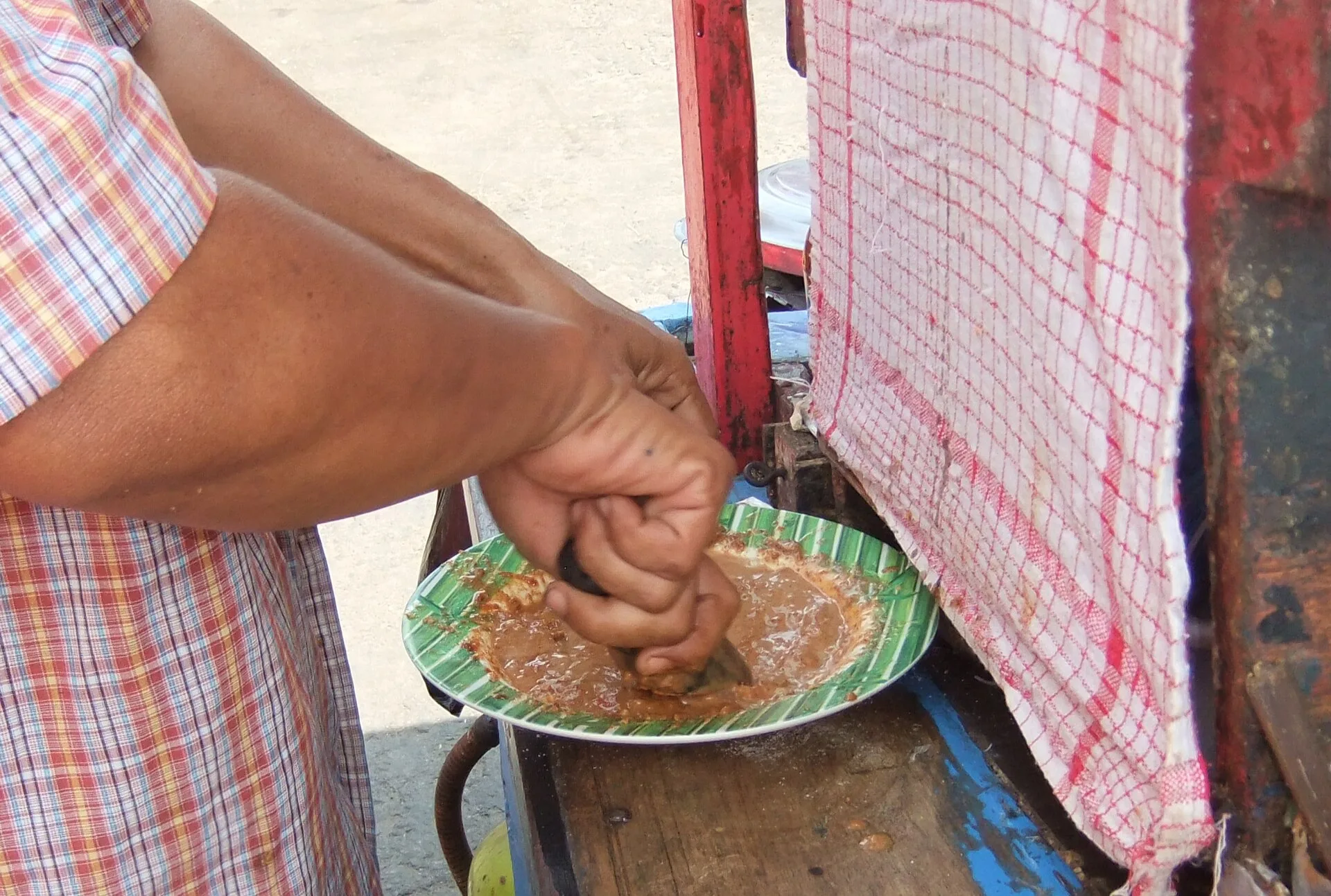 Bumbu kacang : la sauce cacahuète du gado-gado, recette et ratio 8 Un vendeur ambulant de Jakarta écrase une sauce au pilon dans un mortier en pierre posé sur son chariot