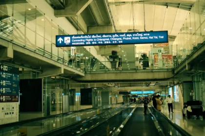 Intérieur de l'aéroport Suvarnabhumi à Bangkok, avec un tapis roulant et les panneaux des vols en correspondance